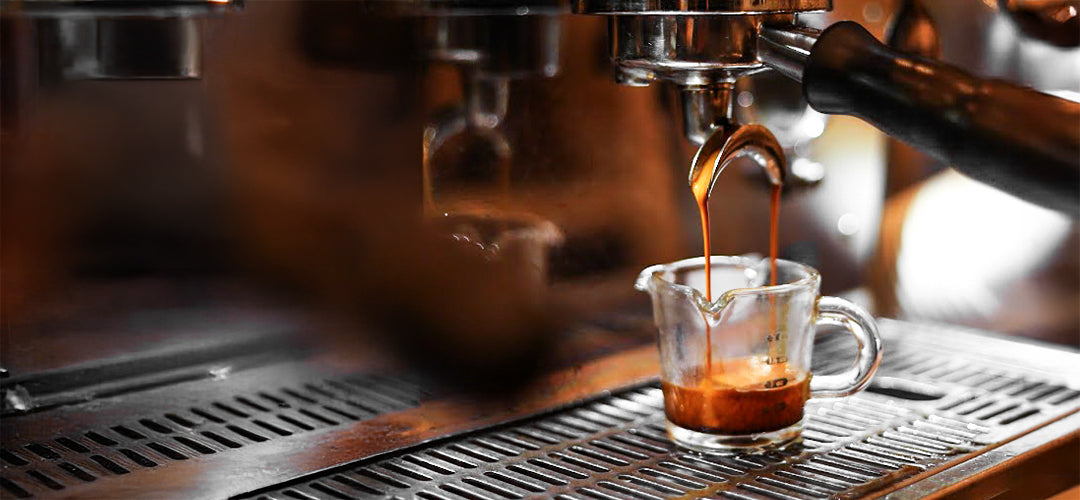 A close-up view of freshly brewed coffee being poured, highlighting the rich color and smooth texture as it flows from the espresso machine, capturing the essence of a perfectly brewed cup at C Market Coffee.