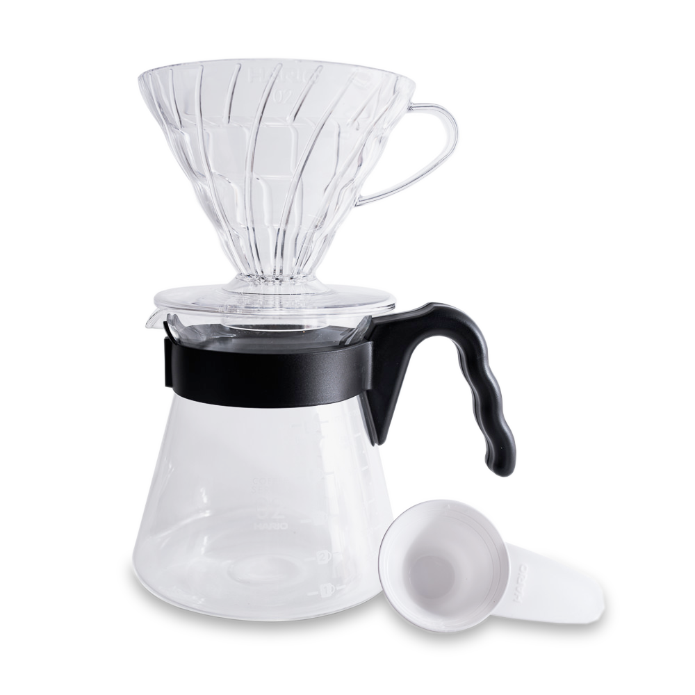 Step-by-step guide for brewing coffee with the V-60 Pour Over method, featuring the copper V-60 brewer. The process involves folding the filter, rinsing it with hot water, and adding 23g of medium-ground coffee. Water is poured in circular motions, allowing the coffee to bloom and de-gas. The process continues with slow, spiraling pours until reaching 360g of water. The brew time is targeted at 3 minutes to produce about 10 oz of coffee.