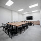 Room view with chairs, desks, and a large TV setup for meetings or presentations.