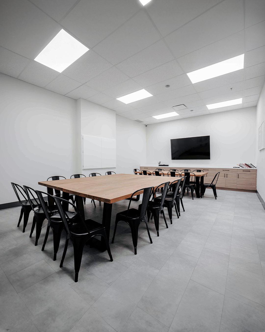 Room view with chairs, desks, and a large TV setup for meetings or presentations.