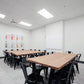 Bright and modern meeting room with large desks, comfortable chairs, and a smart TV for presentations.