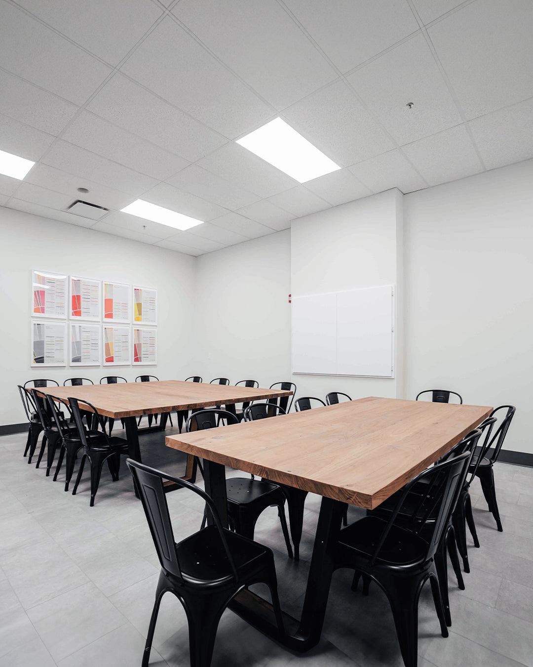 Bright and modern meeting room with large desks, comfortable chairs, and a smart TV for presentations.