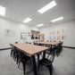 Spacious meeting room with desks, chairs, and an 85” Smart TV setup for presentations.